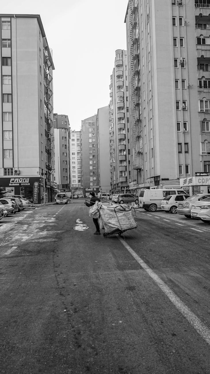 black and white photo of man with large bag crossing street