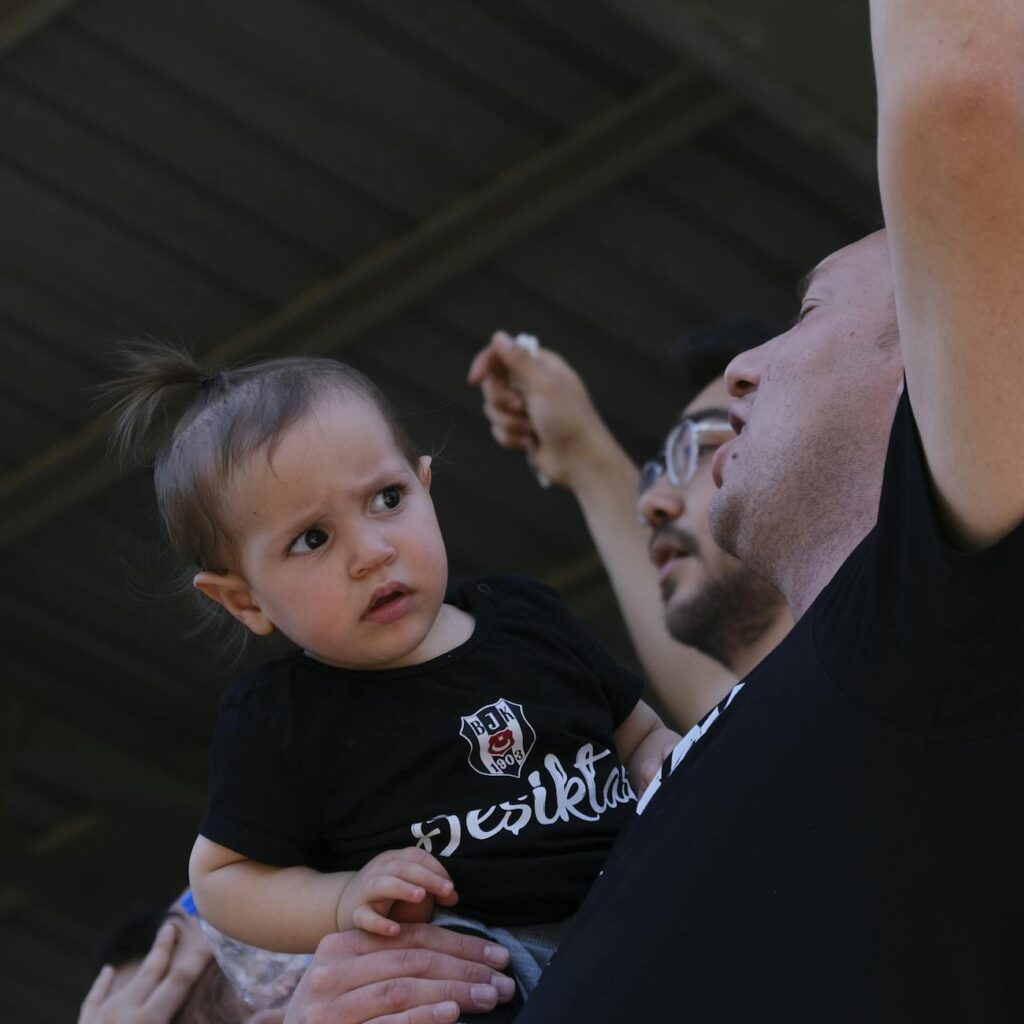 cheering men holding confused toddler