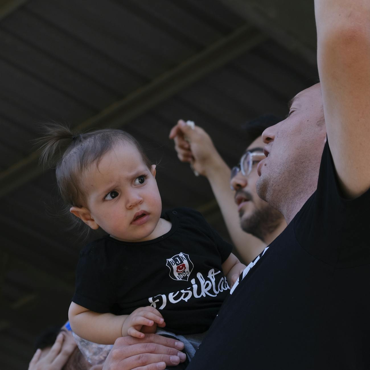 cheering men holding confused toddler